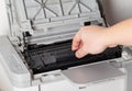 A man takes out a cartridge from a laser printer for maintenance and refilling toner, close-up