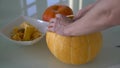 A man takes out the insides of a pumpkin close-up