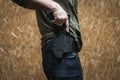 The man takes out a tactical pistol from his holster, close-up photo without a face