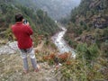 A man takes a photo on a smartphone of mountain river