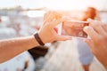 Man takes picture of young woman. She poses on camera and smiles. Brunette stands on pier. There are yachts on each side