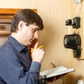 A man records the readings of an electricity meter