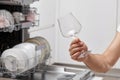 man takes wine glasses out of the dishwasher in the kitchen. Royalty Free Stock Photo