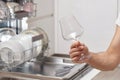 man takes wine glasses out of the dishwasher in the kitchen. Royalty Free Stock Photo