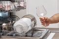 man takes wine glasses out of the dishwasher in the kitchen. Royalty Free Stock Photo