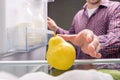 Man takes yellow pear out from refrigerator inside look