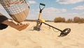 Man taking coins from the sieving sand scoop. searching for precious metals on the sandy beach