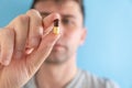 Man taking gastritis, stomach ulcer, heartburn medicine capsule or pill on blue background. Focus on the drug Royalty Free Stock Photo