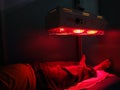 A man taking Low level laser therapy on his leg using red therapy light Royalty Free Stock Photo
