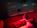 A man taking low level laser therapy on his leg using red therapy light