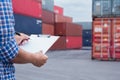 Man taking note checking cargo shipping at container yard area.