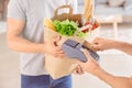 Man taking off money for food delivery from client's credit card using bank terminal