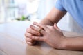 Man taking off wedding ring at wooden table indoors, closeup. Divorce concept Royalty Free Stock Photo