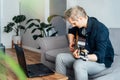 Man taking online guitar lessons with a laptop at home sitting on the gray couch, sofa in the living room. He watching Royalty Free Stock Photo