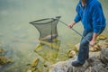 Man taking out a fish he just caught in the lake using a big large fishing net Royalty Free Stock Photo