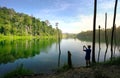 Man taking pciture with his cellphone of a beautiful landscape of lake and green forest Royalty Free Stock Photo