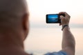 Man taking photo amazing sunset using smartphone camera, tourist hand holding Royalty Free Stock Photo