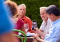 Man Taking Photo As Group Of Friends Talking Around Table At Summer Dinner Party In Garden At Home Royalty Free Stock Photo