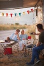 Man taking a photo of a couple. Sitting outdoors in front of camper rv. Fun, togetherness, lifestyle, love concept