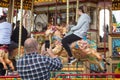 Man taking a photo on a mobile phone of teenager riding on a carousel horse on fairground ride at amusement fair Royalty Free Stock Photo