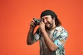 Man taking photo on retro camera. Male tourist with camera in studio on orange background close up.