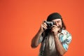 Man taking photo on retro camera. Male tourist with camera in studio on orange background close up.