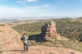 Young man taking a photo of a Rodeno Boulder in Perecens, Teruel, Spain.