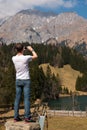 Man taking photo of Small Mountain lake on smart phone in Alps