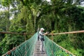 Man taking photo with at suspension bridge in tree top canopy walkway in Danum rain forest Royalty Free Stock Photo