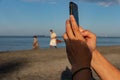 Man taking photos with cell phone of the sea Royalty Free Stock Photo