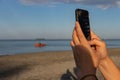 Man taking photos with cell phone of the sea Royalty Free Stock Photo
