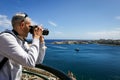Man taking photos of Grand Harbour from a view point balcony at the Upper Barakka Gardens,Valletta, Malta. .
