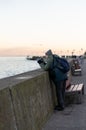Man taking photos with his camera by a barrier at the seaside in Gdynia, Poland.