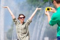 Boyfriend taking a picture of his girlfriend while sitting background the fountain. Young man making photo of woman on Royalty Free Stock Photo