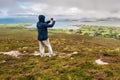 Man taking picture on his smart phone of view on Clew Bay from Croagh Patrick Royalty Free Stock Photo