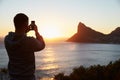 Man Taking Picture Of Sun Setting Over Sea On Mobile Phone Royalty Free Stock Photo