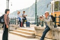 A man taking a picture of a woman with a mobile phone and another couple with suitcases