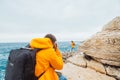 man taking picture of woman in yellow raincoat at the cliff near sea Royalty Free Stock Photo