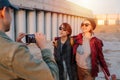 Man taking pictures of two young happy short-haired women with skateboards