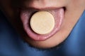 Man taking pill, mouth open with tongue sticking out.