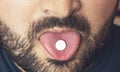 Man taking pill, tablet of drugs or medicine on tongue with open mouth. Painkiller treatment or party narcotic