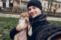 man taking selfie with adorable brown puppy with amazing blue eyes on background of autumn park. space for text. faithful friend Royalty Free Stock Photo