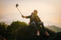 man is taking a selfie with his cell phone while sitting on a rock Royalty Free Stock Photo