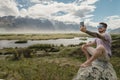 Man taking a selfie with mobile at Glenorchy, beutiful mountain view. New Zealand landscape