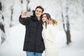 Man taking selfie photo young romantic couple smile snow forest outdoor winter pine woods. Couple make selfie.