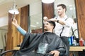 Man Taking Selfportrait On Smartphone While Hairdresser Styling