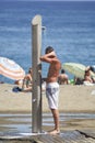 A man taking a shower on the beach in Malaga in Spain during the summer