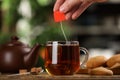 Man taking tea bag out of cup with beverage at wooden table, closeup Royalty Free Stock Photo