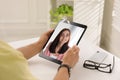 Man talking with beautiful woman using video chat on tablet at white table, closeup. Online dating Royalty Free Stock Photo