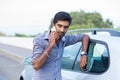 Man talking on a cell phone leaning on the door of his car Royalty Free Stock Photo
